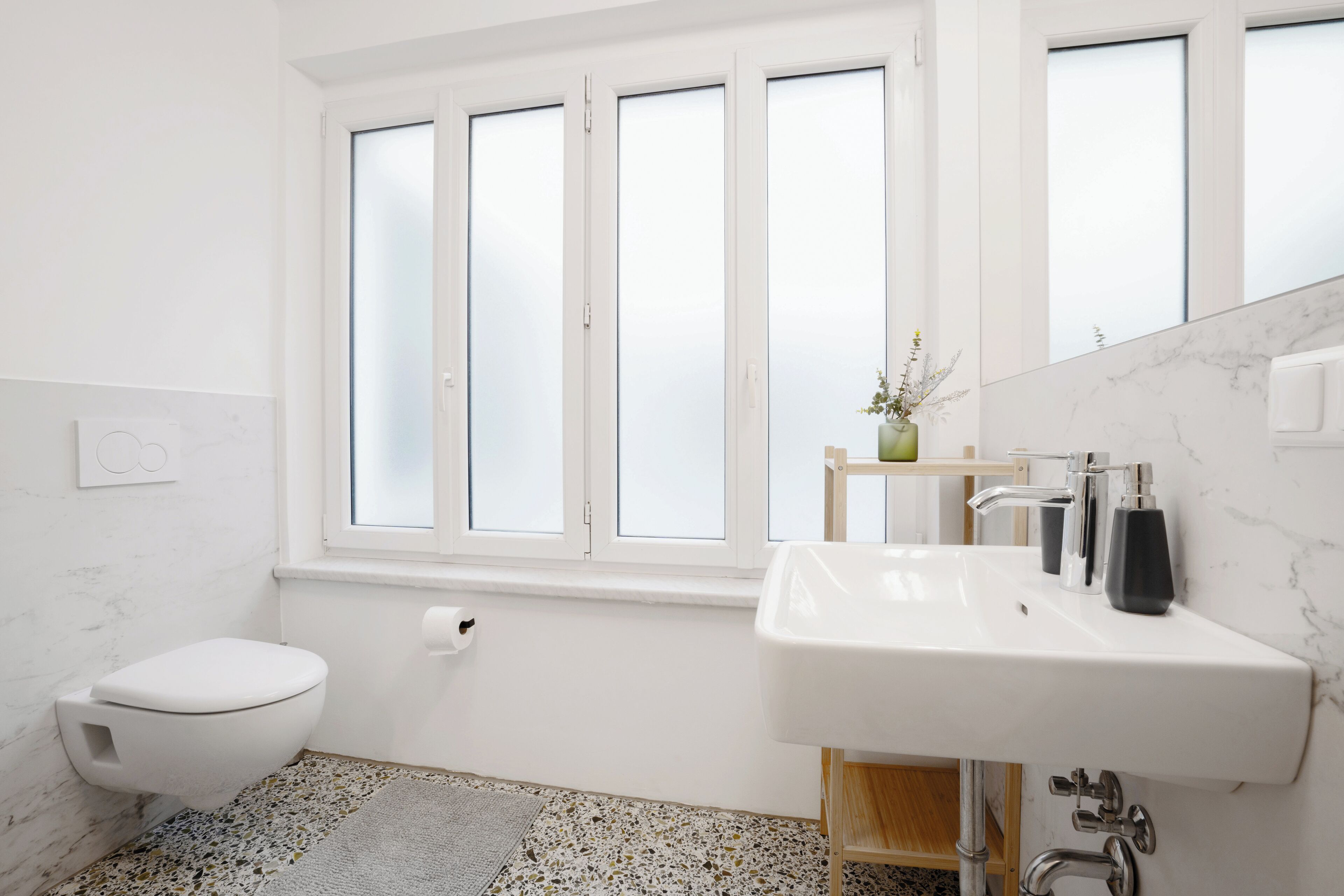 A modern bathroom with a toilet, sink, and window.