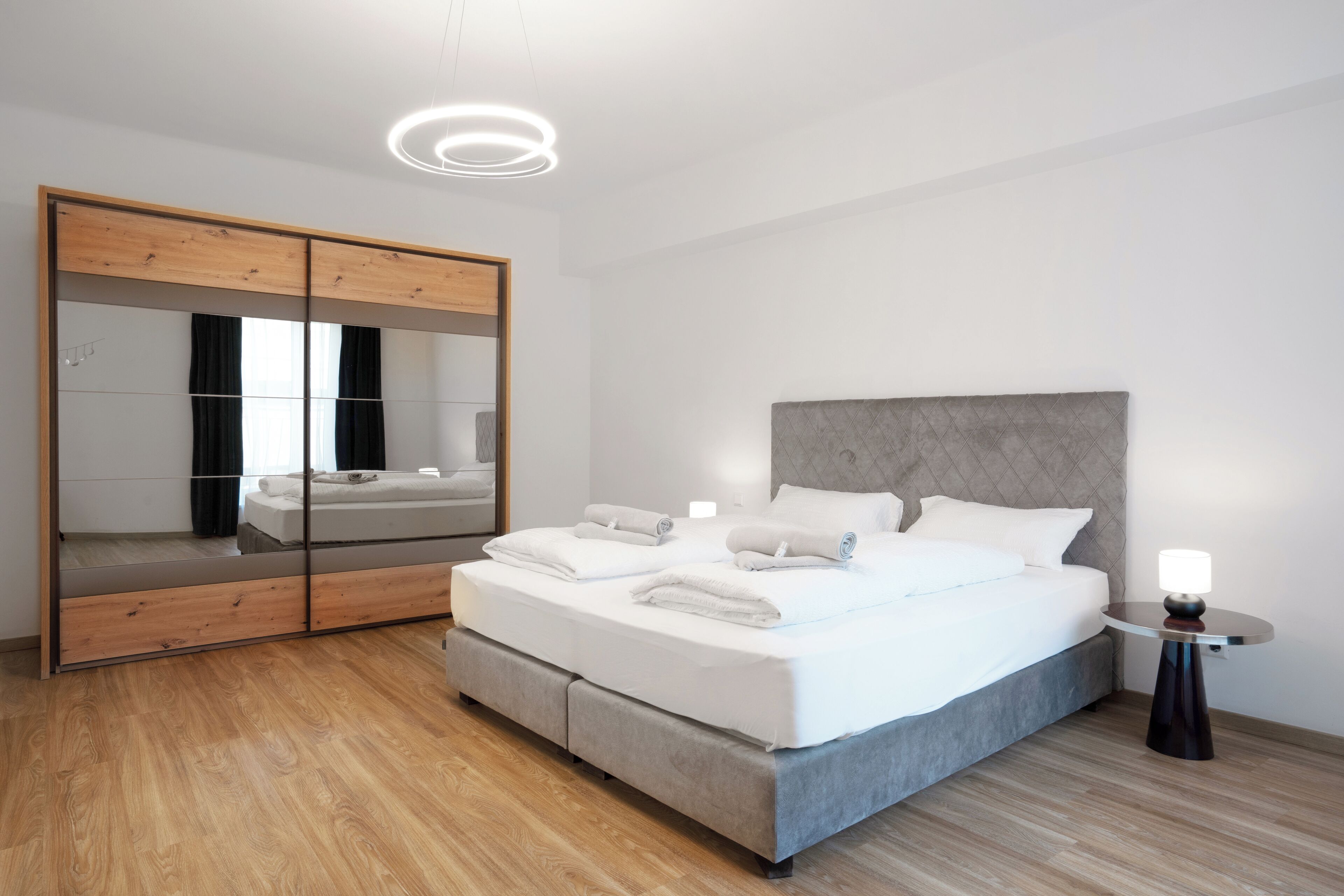 Una camera da letto moderna con un letto grande, un'armadio in legno e un comodino con una lampada.