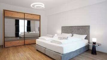 Una camera da letto moderna con un letto grande, un'armadio in legno e un comodino con una lampada.