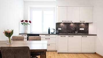 A modern kitchen with white cabinets, a black countertop, and a window above the sink.