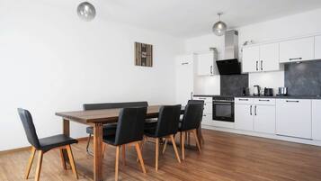 A modern kitchen with white cabinets, a wooden dining table, and black chairs.