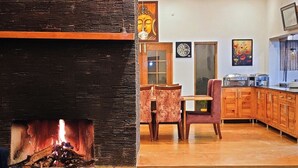 A spacious living area with a fireplace, a wooden staircase, and a dining area with a table and chairs. - aMALA Villa - Six Bedroom Luxurious Villa with Himalayan View (Kaudia Range)