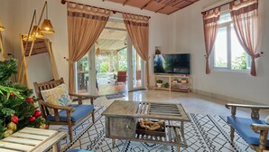 A spacious living room with a large TV, wooden furniture, and a Christmas tree. - Unique Three bedroom with three Bathroom House in An Bang  (Thành phố Hội An)