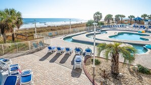 Un espace piscine avec des chaises longues et vue sur la plage.