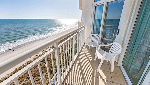 Un balcon avec vue sur la plage et l’océan.