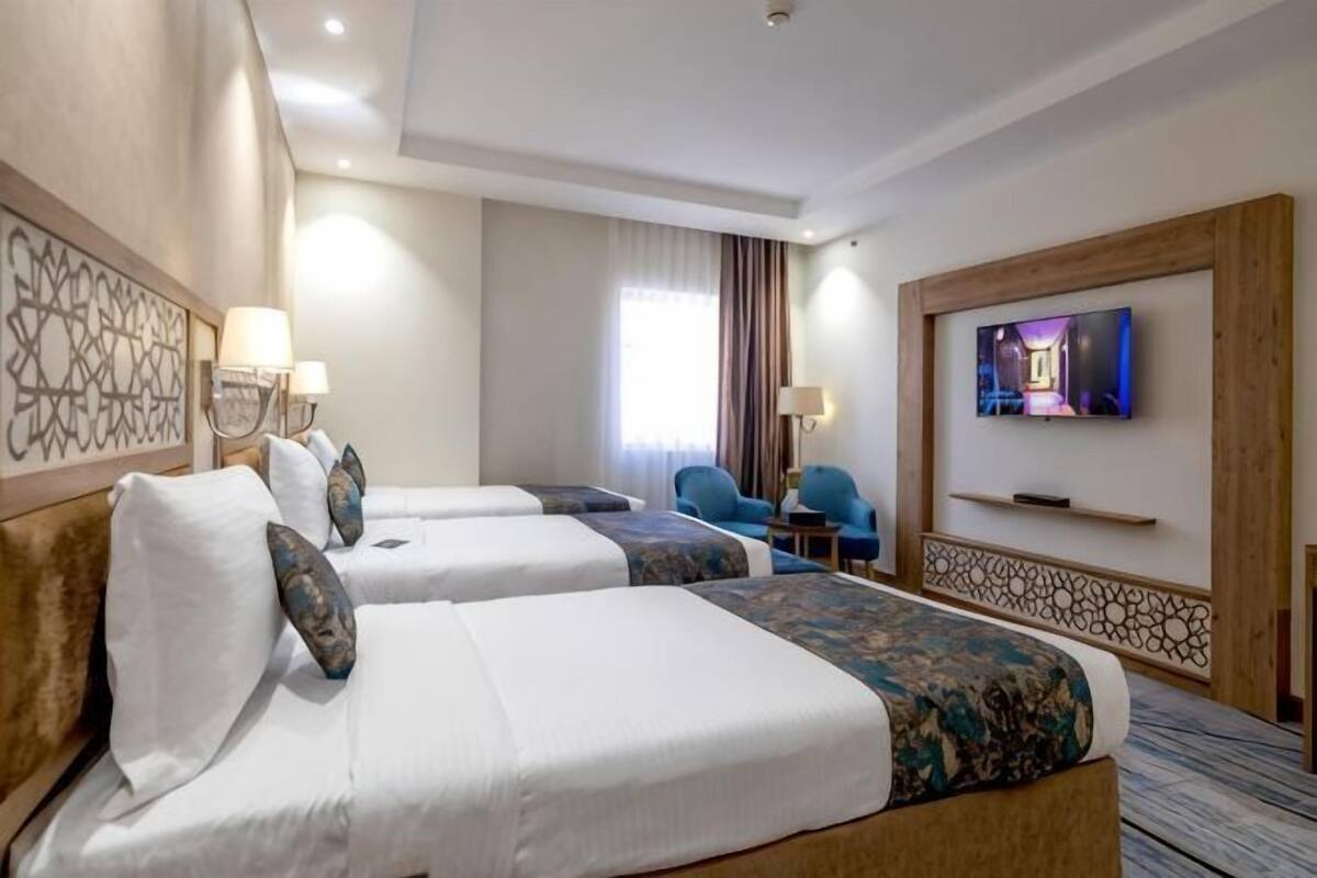 A hotel room with two beds, a TV, a desk, and a chair.