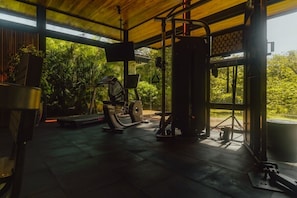 A gym with exercise equipment, a large window, and a view of greenery.