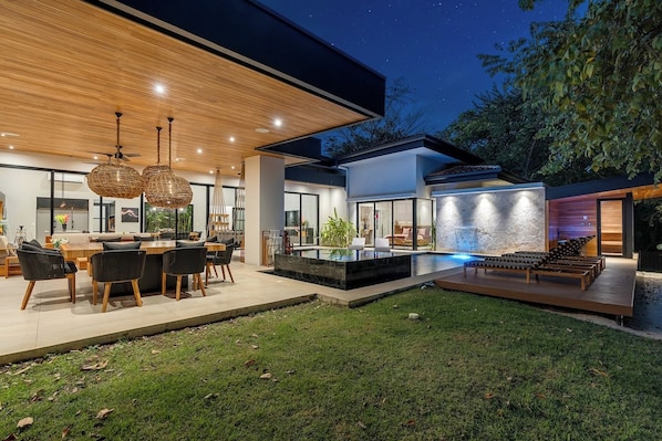 A modern house with a dining area, a swimming pool, and a lounge area.
