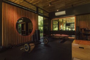 A gym with a mirrored wall, weightlifting equipment, and a bench.