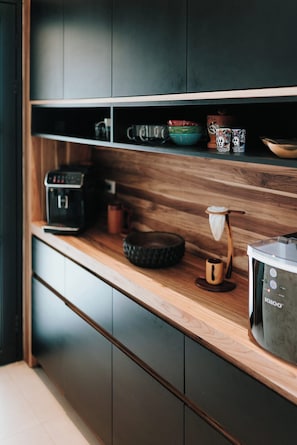A kitchen with a wooden countertop, a coffee machine, and various mugs and bowls.