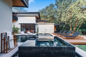 A modern outdoor pool area with lounge chairs and a building with large windows.
