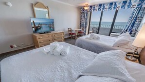 A hotel room with two beds, a TV, a desk, and a balcony with a view of the sea. - Amazing Views, Coastal  Paradise Experience! (Myrtle Beach)