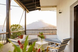 A balcony with a white table, striped chairs, and potted plants. - EMPHASIS Traditional House (Amari)