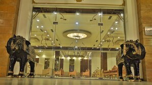 Una entrada imponente con dos esculturas ornamentales de elefantes a cada lado de la puerta, un gran candelabro y un cartel que dice "SAPPHIRE".