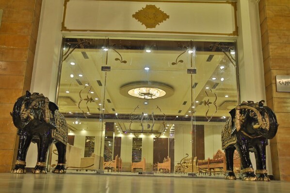 A grand entrance with two ornate elephant statues flanking the doorway, a large chandelier, and a sign reading "SAPPHIRE". - Hotel Red Sapphire (Moradabad)