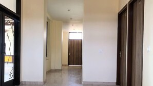 Un pasillo con ventilador de techo, una puerta al final y suelo de mármol.