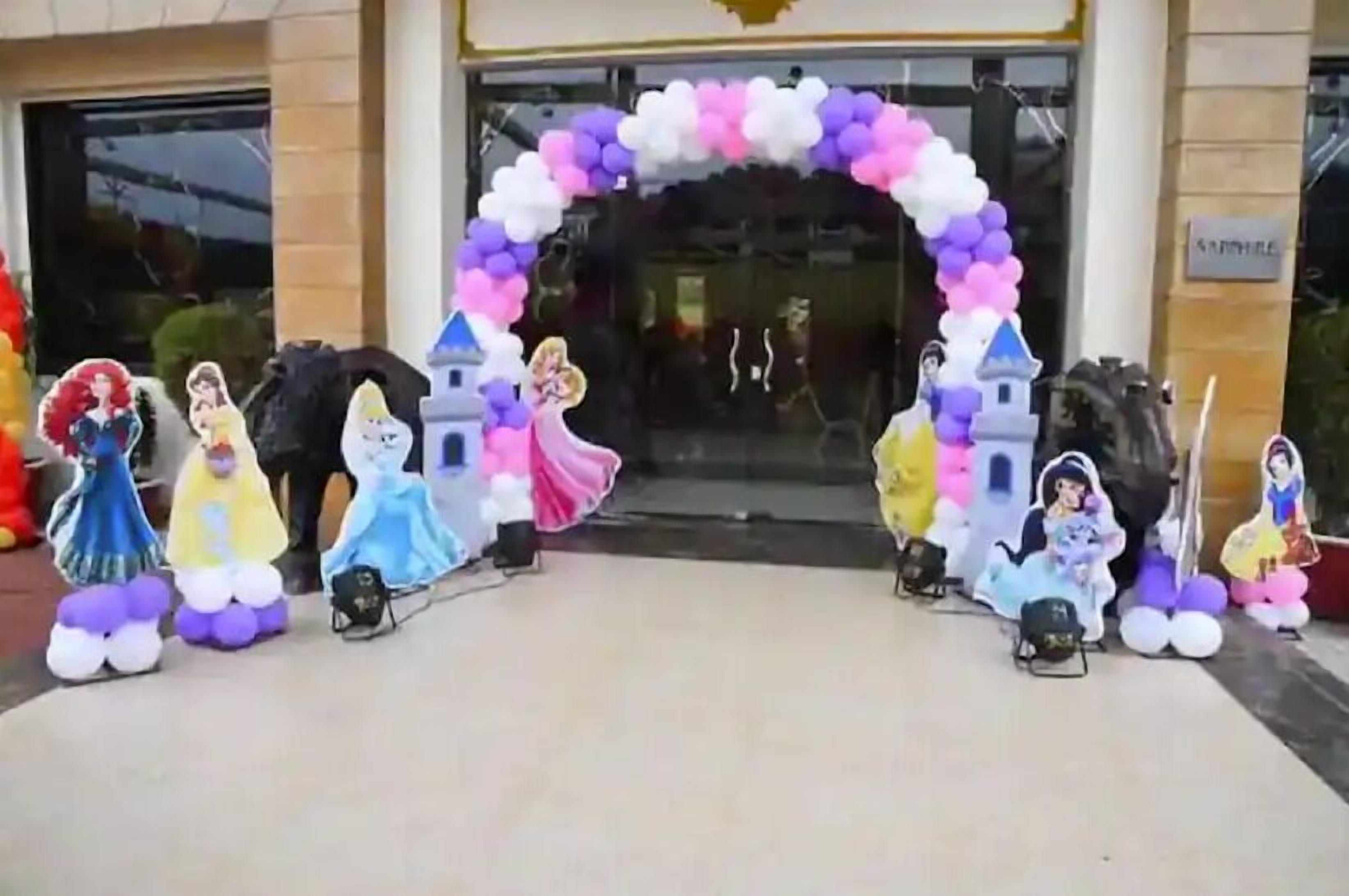 Entrada de hotel con un arco decorativo de globos y recortes de princesas de Disney.