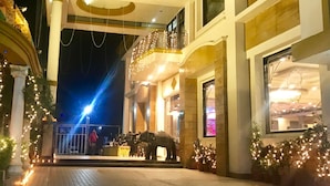 Un edificio de varios pisos con un balcón, decorado con luces colgantes y plantas en macetas.