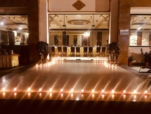 A hotel lobby with a reception desk, a chandelier, and a row of tables and chairs. - Hotel Red Sapphire (Moradabad)