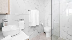 A modern bathroom with a large white sink, a toilet, and a glass shower enclosure. - Wine Down - Small family getaway (Kiama)