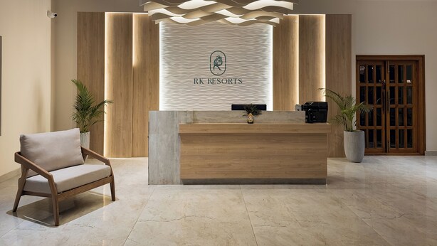 Un mostrador de recepción moderno con un logotipo, paneles de madera y una planta en maceta.