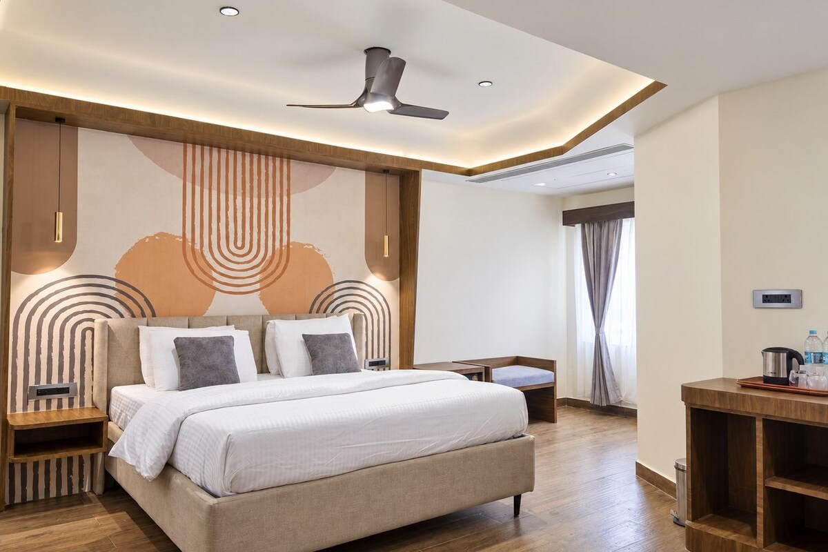 A modern hotel room with a large bed, a desk, and a ceiling fan.