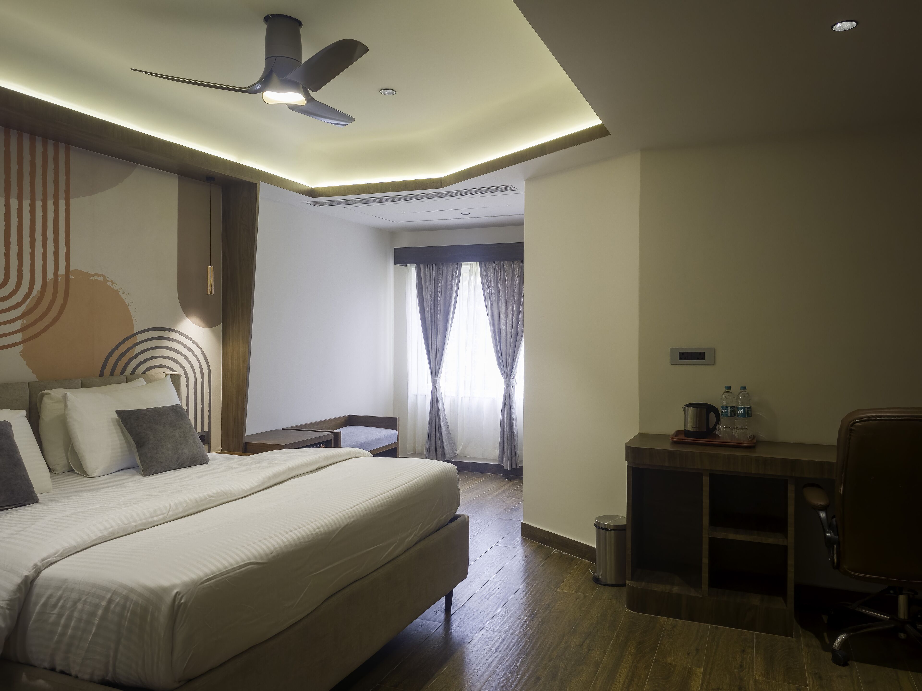 Una habitación de hotel con cama, escritorio, silla y ventilador de techo.