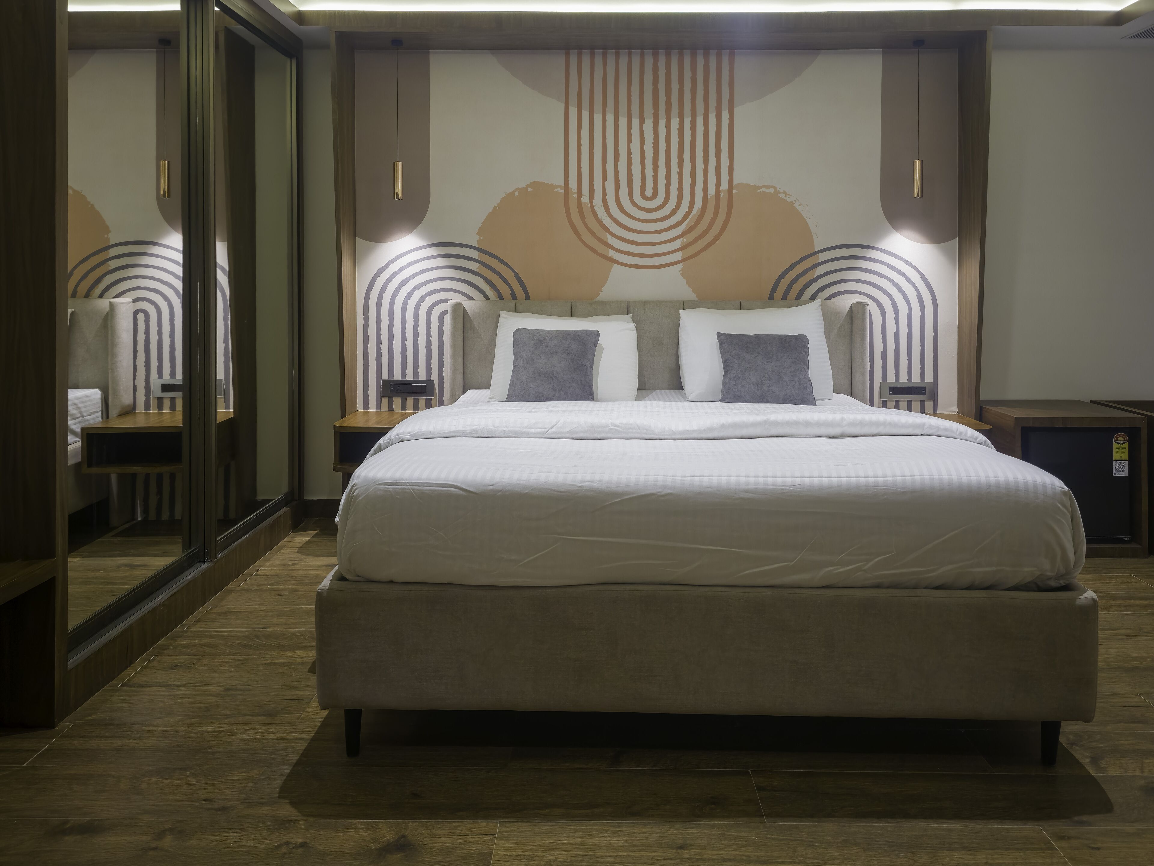 A modern bedroom with a large bed, bedside tables, and a decorative wall.