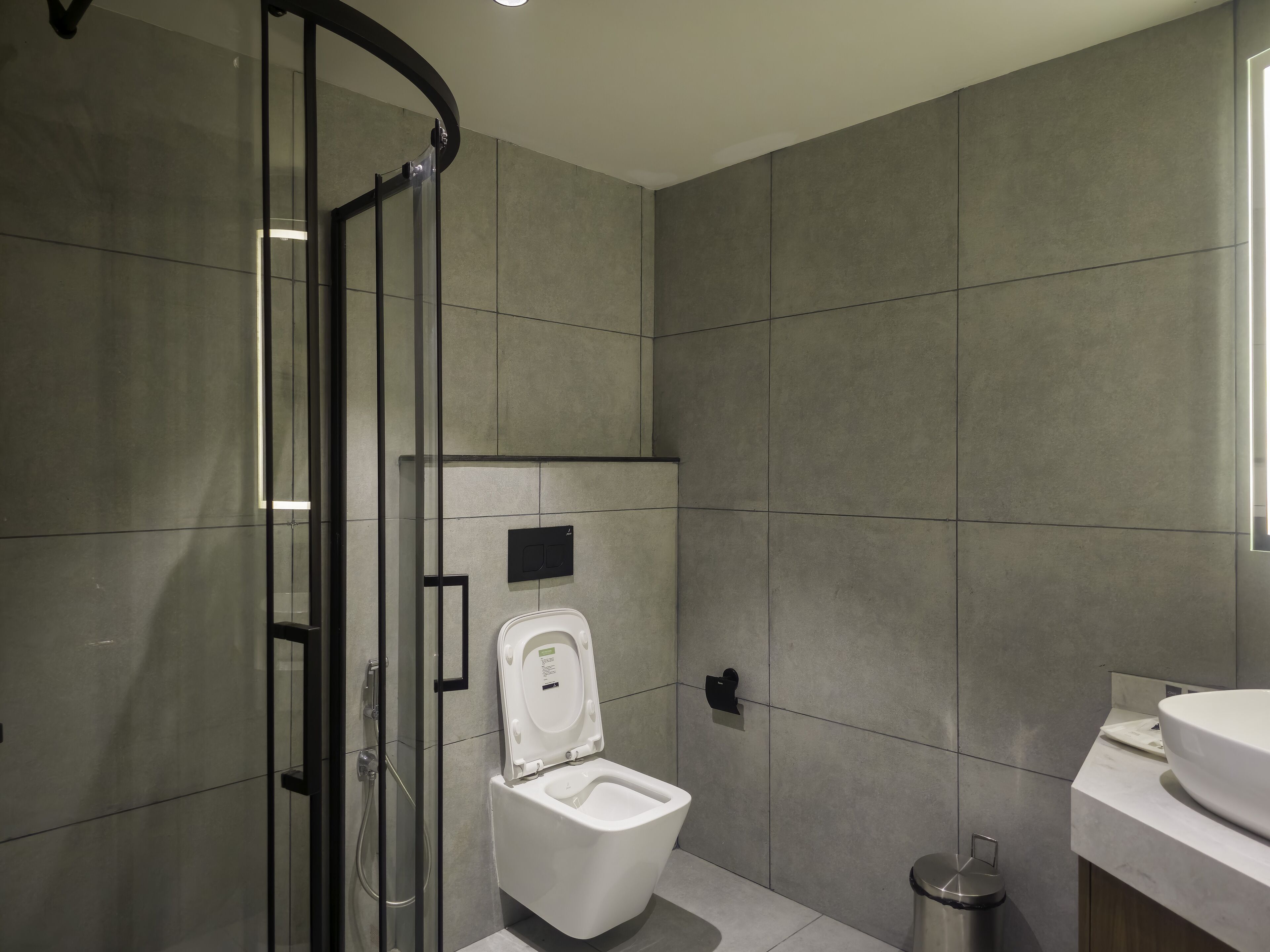 Un baño moderno con cabina de ducha de vidrio, inodoro y lavamanos.