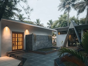 A modern house with a stone wall, a wooden door, and a small garden area. - RK Resorts (Karaikal)