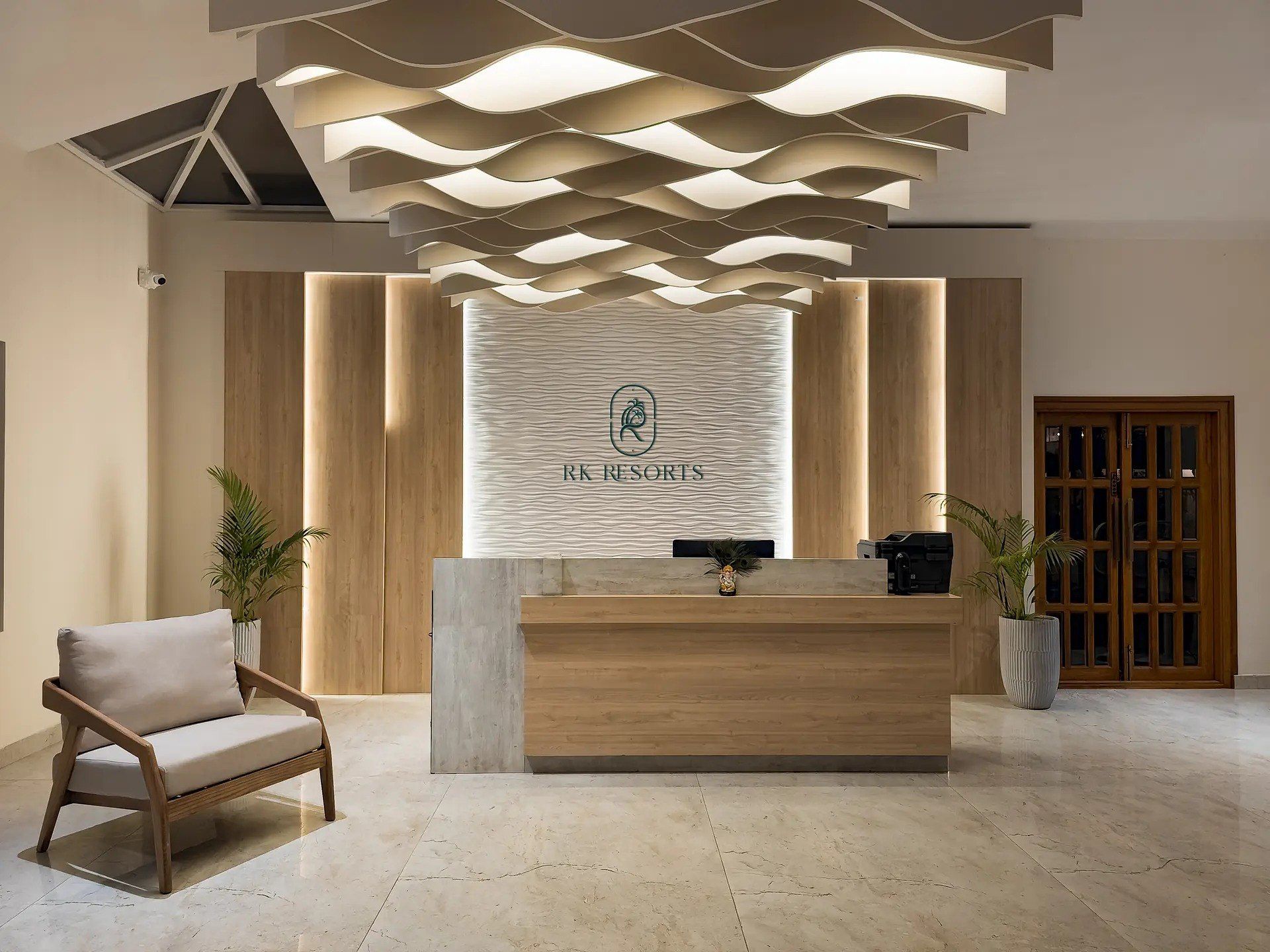 A modern reception desk with a logo, a wooden reception area, a chair, and potted plants.