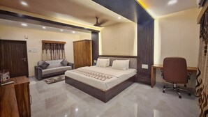 Un dormitorio moderno con una cama grande, un sofá, un escritorio y un armario.