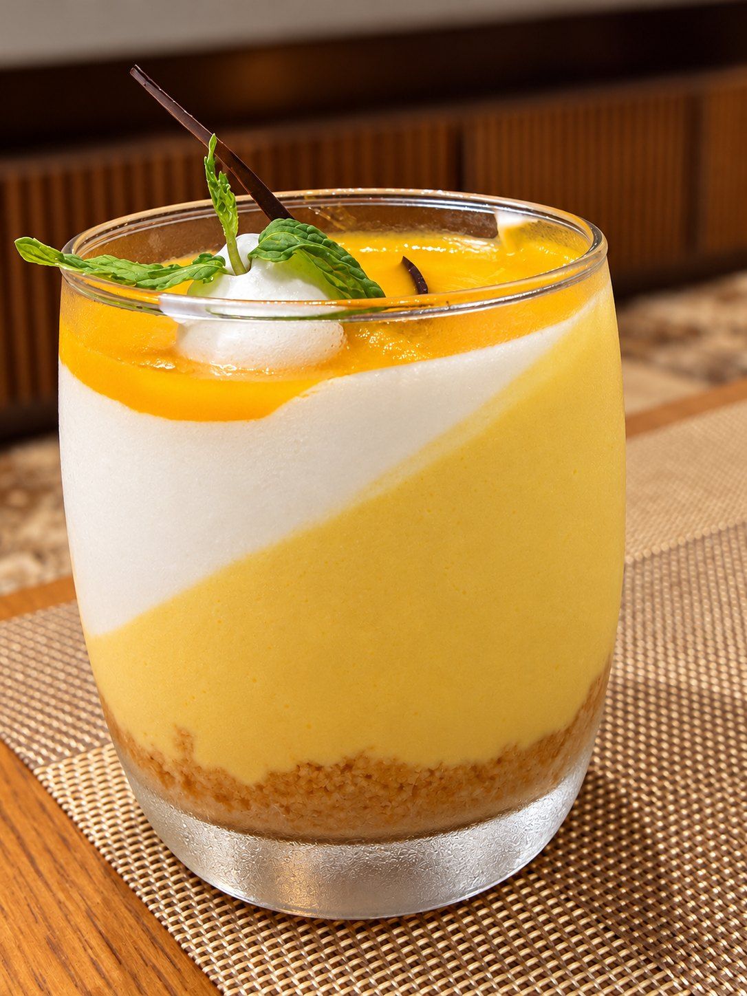 A layered dessert in a clear glass with a mint garnish.