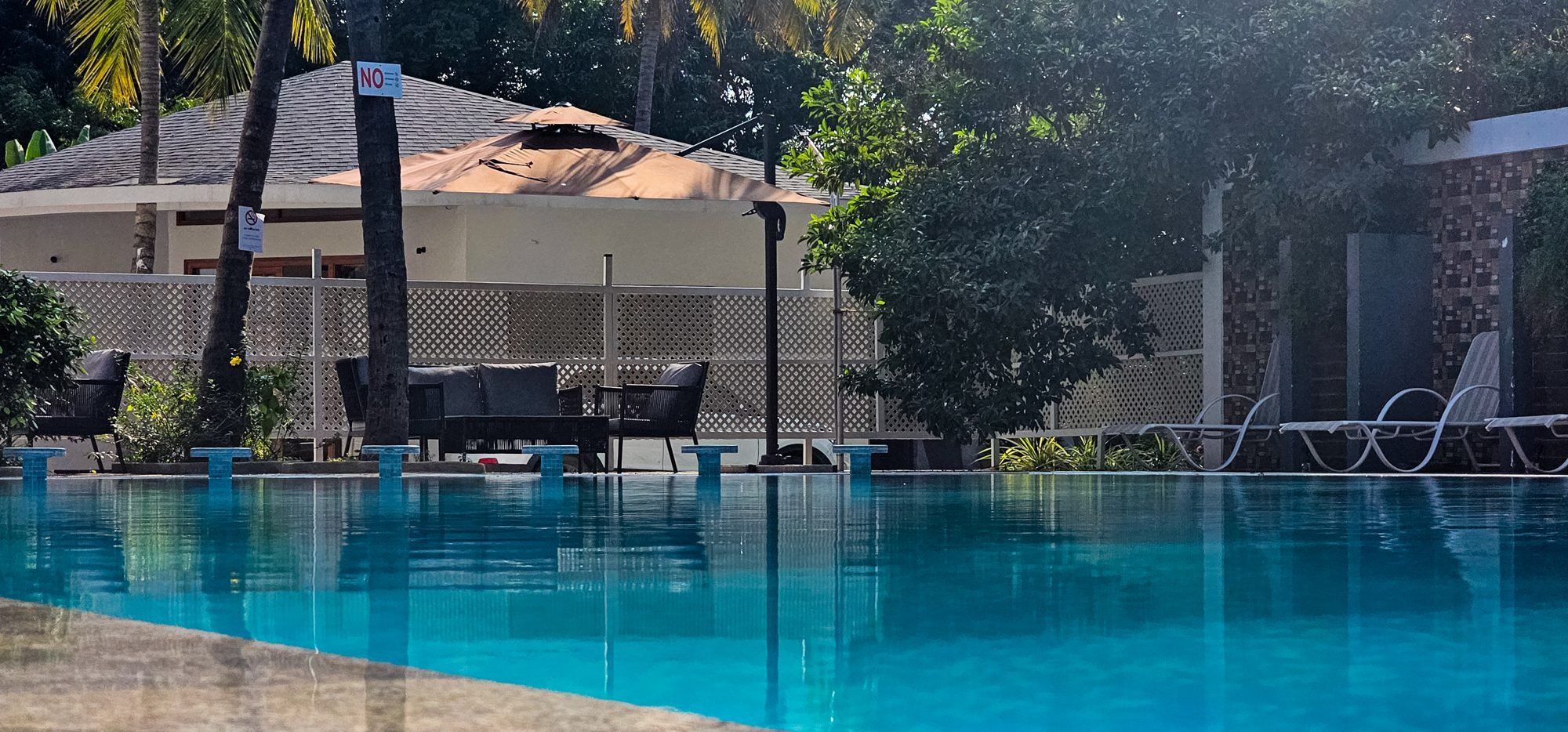 A swimming pool with lounge chairs and a covered seating area.