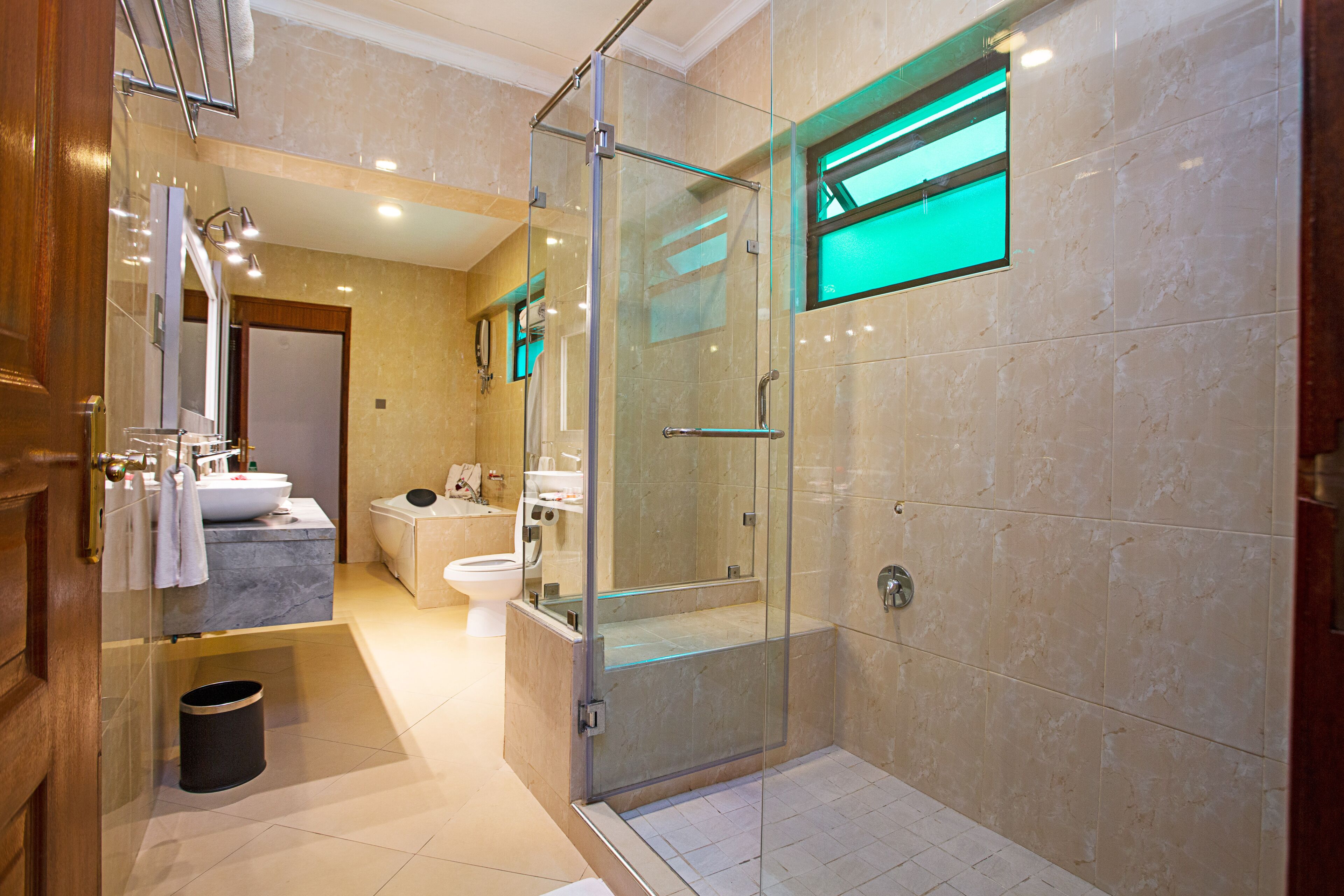 A modern bathroom with a glass-enclosed shower, a marble sink, and a toilet.
