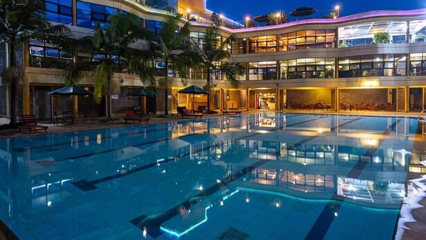 A hotel with a large indoor pool, multiple floors, and outdoor seating areas. - Roswam Hotel (Kerugoya)