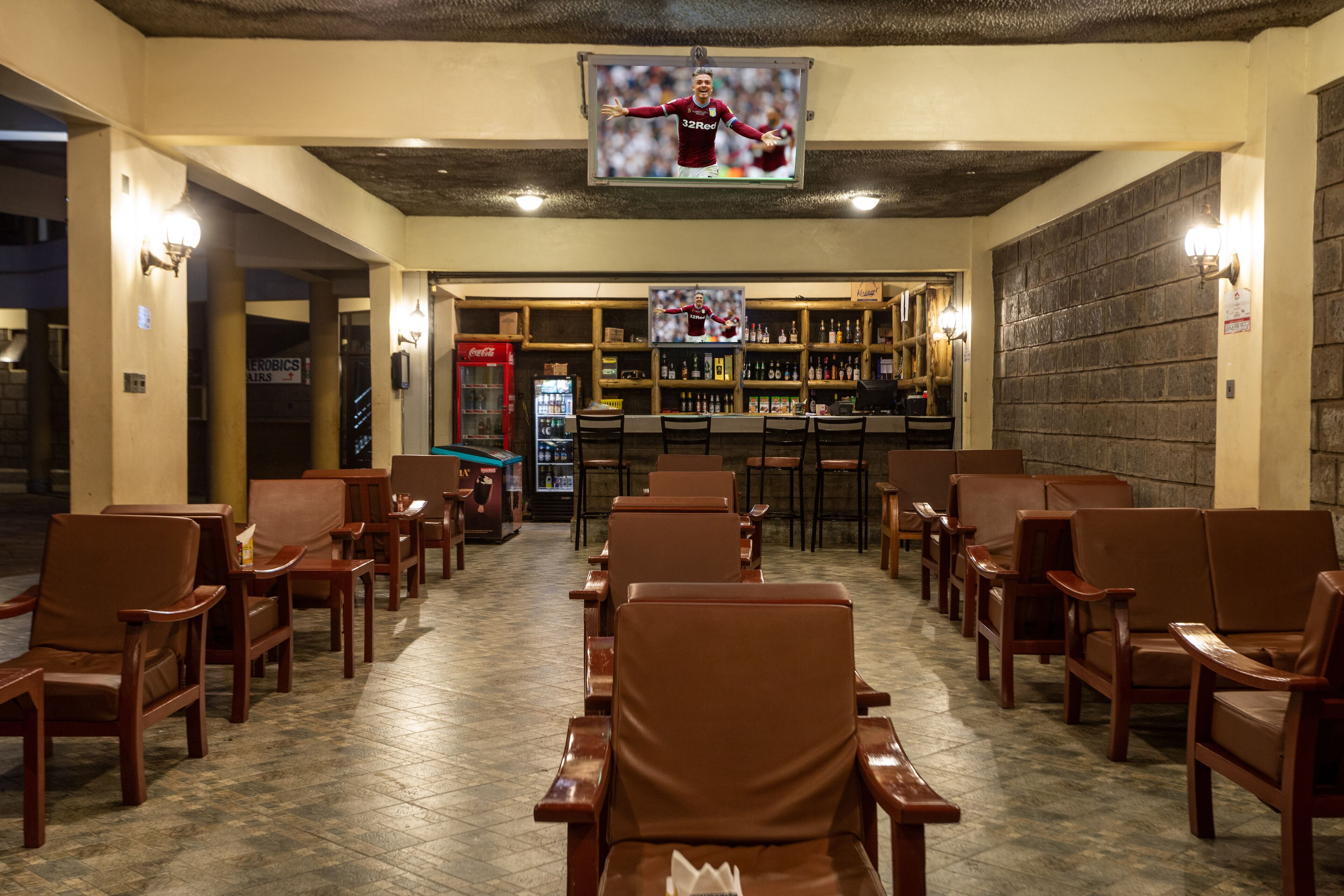 A bar area with wooden chairs and a counter with bottles.