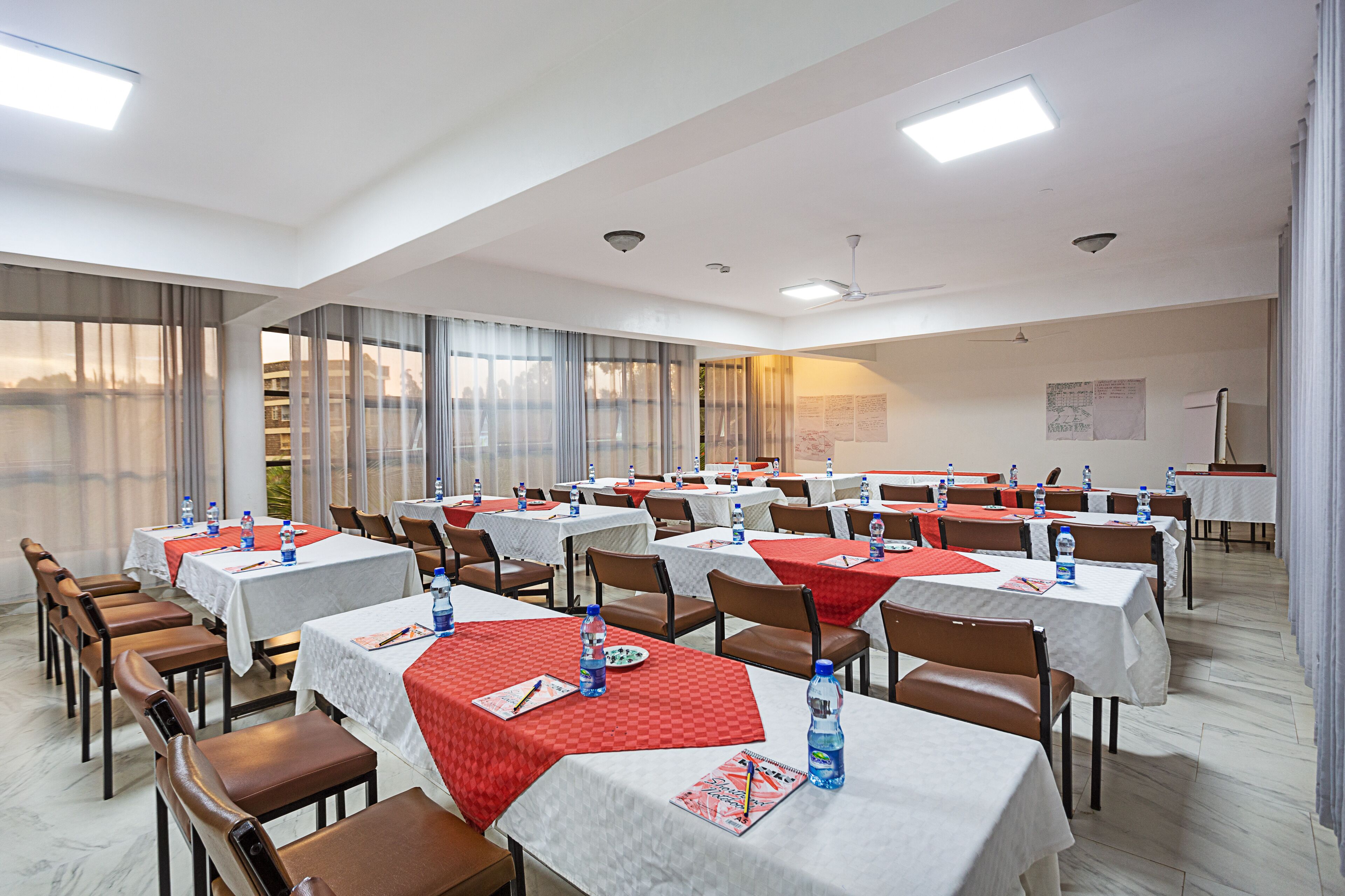 A conference room with multiple tables, chairs, and water bottles.