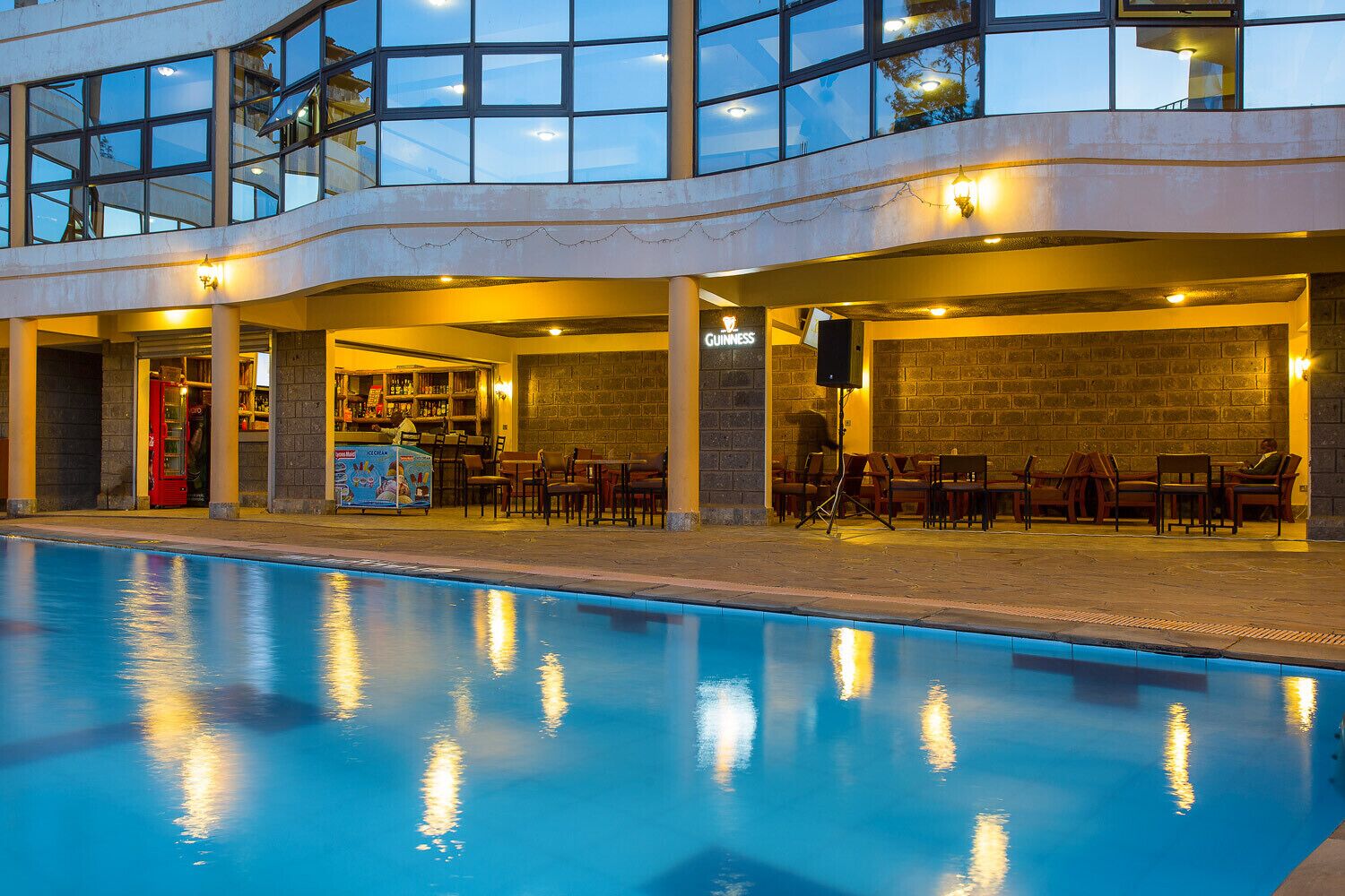 Zona junto a la piscina con bar, asientos y un letrero de Guinness.