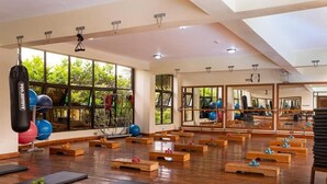 A spacious gym with wooden flooring, exercise mats, and various fitness equipment. - Roswam Hotel (Kerugoya)