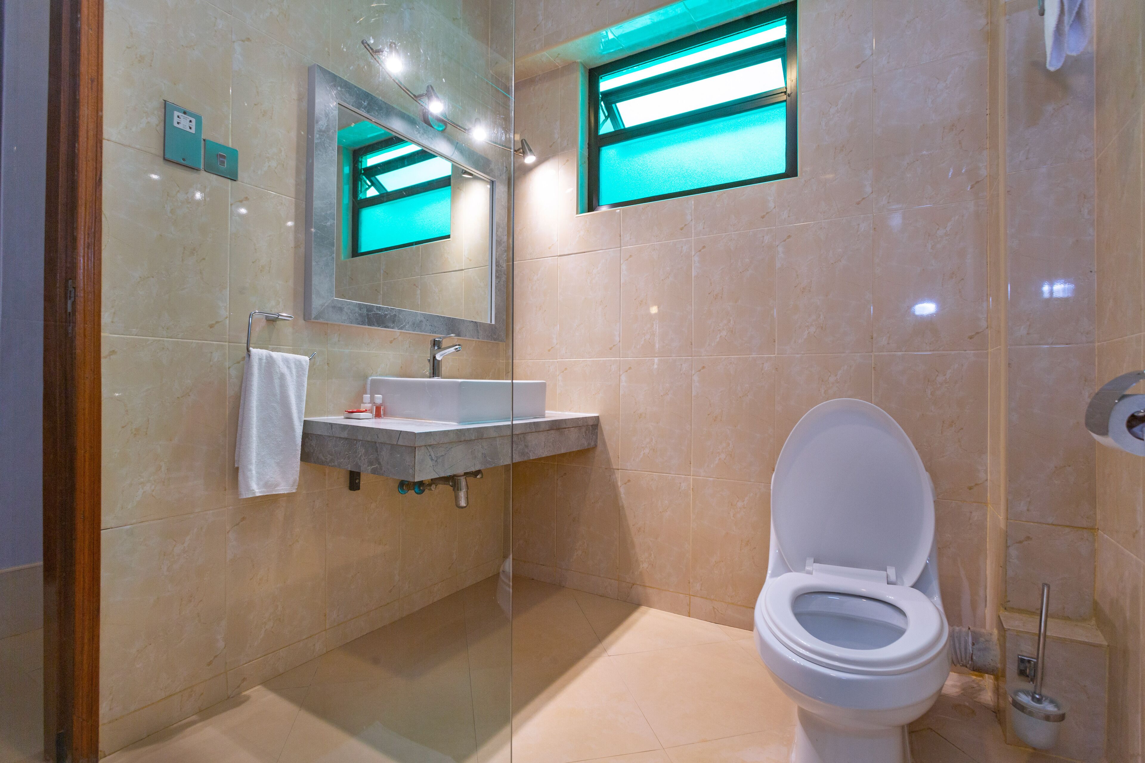 A modern bathroom with a white toilet, a marble sink, and a glass-enclosed shower area.