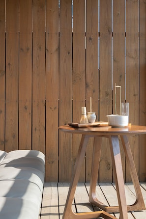Une table en bois, sur laquelle se trouvent un bol blanc, une bouteille et un récipient en verre, le tout adossé à un mur en bois.