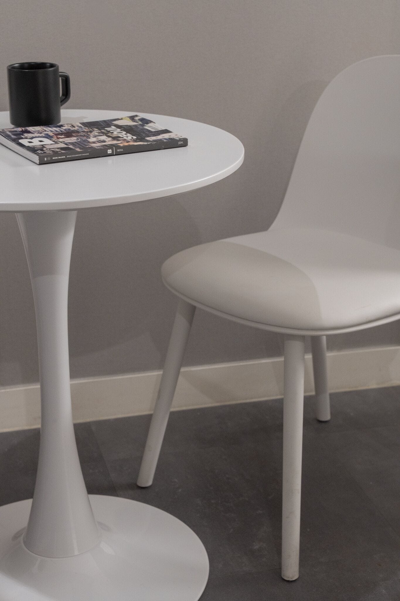 A white table with a black mug and a magazine.