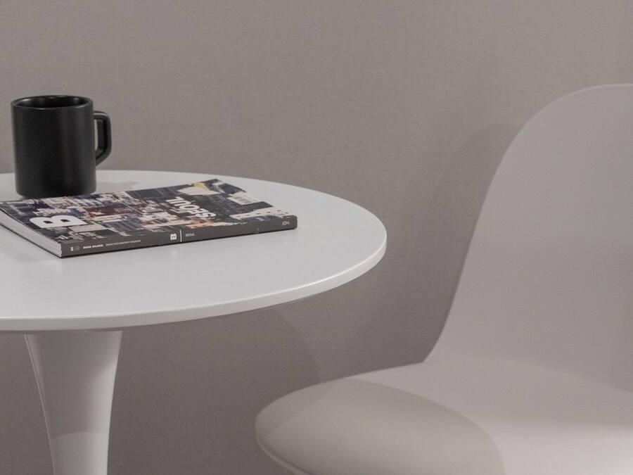 A white table with a black mug and a magazine.