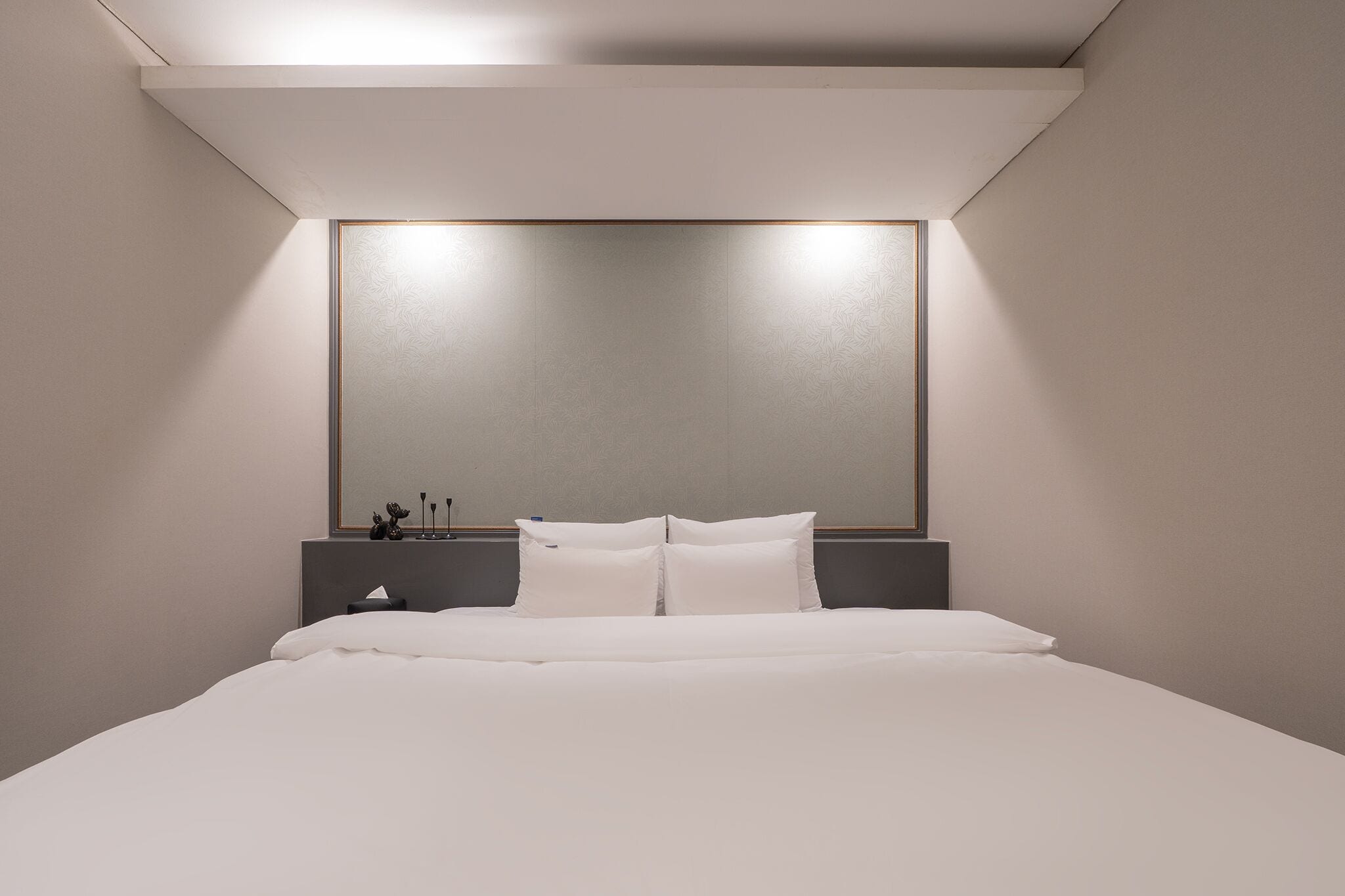 Una habitación de hotel moderna con una cama grande, una mesita de noche y un espejo fijado a la pared.