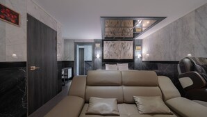 Une chambre d’hôtel moderne dotée d’un canapé, d’un fauteuil massant et de murs en marbre.