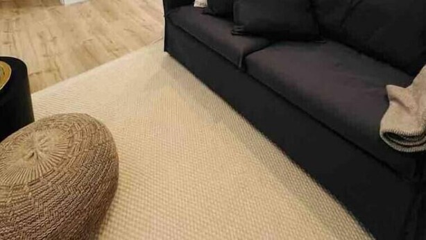 A modern living room with a dark sofa, a round ottoman, and a dining area with a table and chairs. - Schöner Wohnen im Stadtkern (Paderborn)
