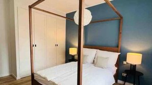 A four-poster bed with a wooden frame, white bedding, and two bedside tables with lamps. - Schöner Wohnen im Stadtkern (Paderborn)