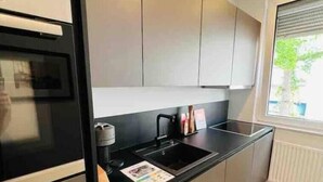 A modern kitchen with a black countertop, stainless steel appliances, and light-colored cabinets. - Schöner Wohnen im Stadtkern (Paderborn)