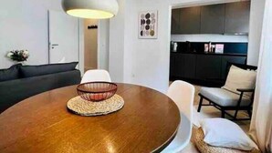 A modern dining area with a round wooden table, white chairs, and a hanging light fixture. - Schöner Wohnen im Stadtkern (Paderborn)